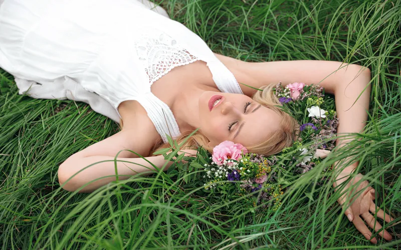 Boudoir wedding photography of a bride lying in grass field in white dreamy gown