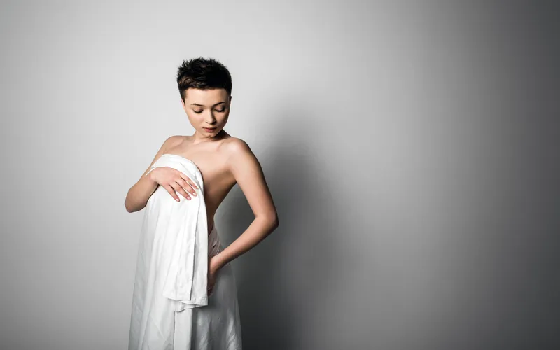 Boudoir wedding photography of a bride wrapped in fabric against a plain backdrop