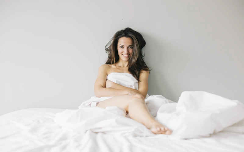 woman draped in sheets posing for her boudoir photoshoot