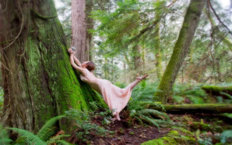 Model posing among trees for a nature-inspired figure photography shot.