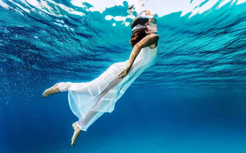woman in a white dress posing for her fine art photoshoot underwater