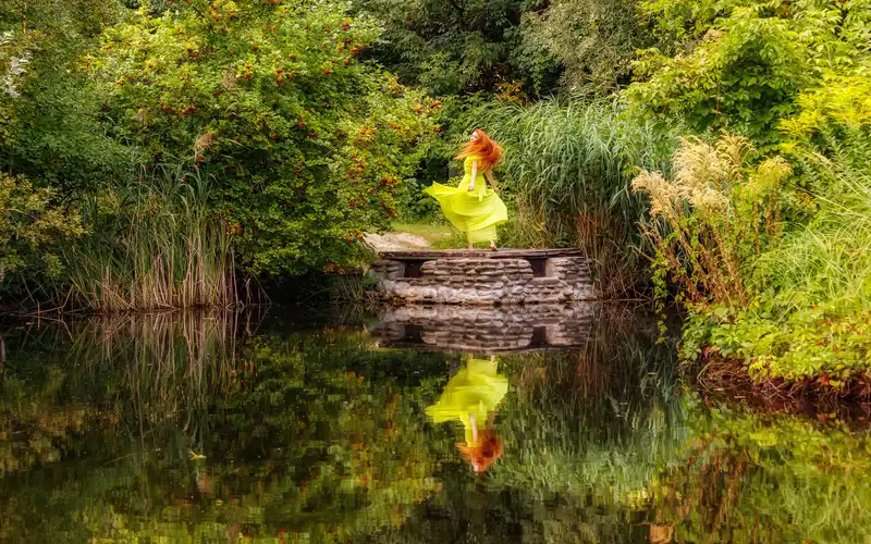 Model's reflection captured on water for creative figure photography poses.