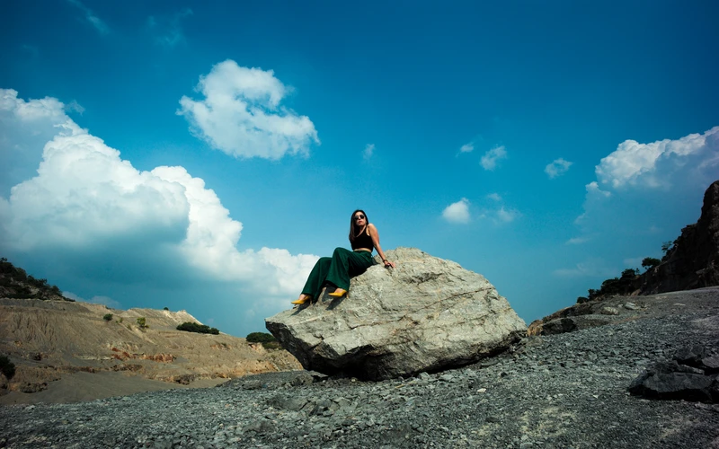 Model posing on boulders to add scale to human figure poses photography.