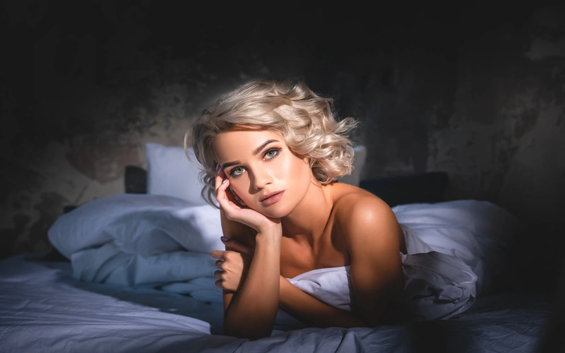 woman with curly blonde hair posing on the bed