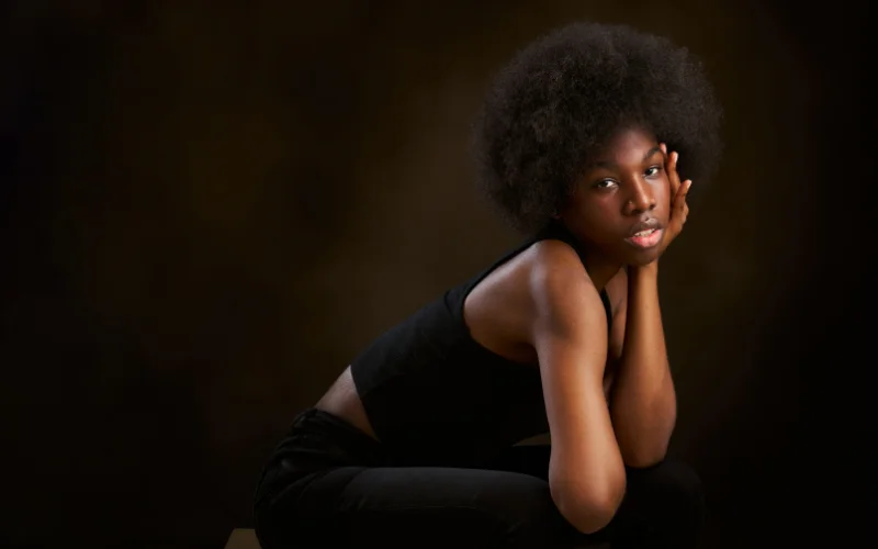 Model captured in a quiet, introspective moment, a popular implied photoshoot pose that conveys vulnerability through body language