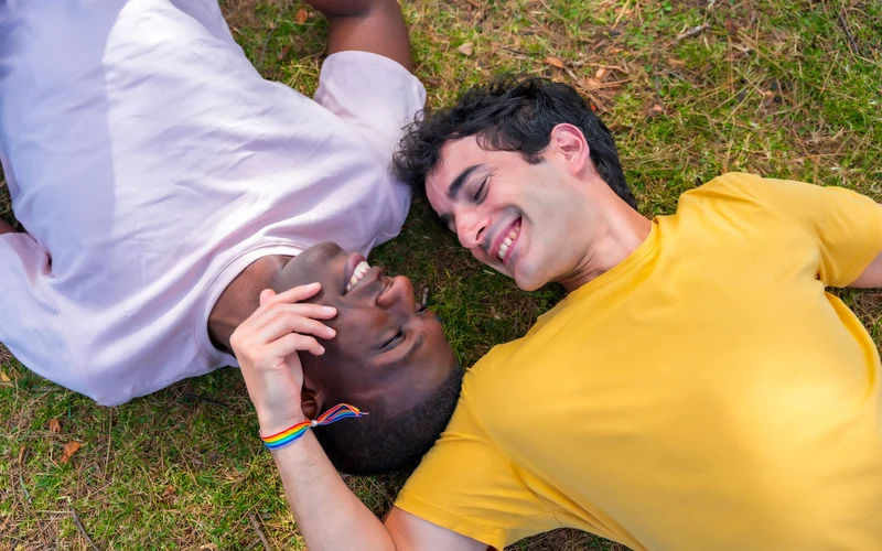 Gay couple lying on the grass together, laughing during an outdoor gay couple photography session