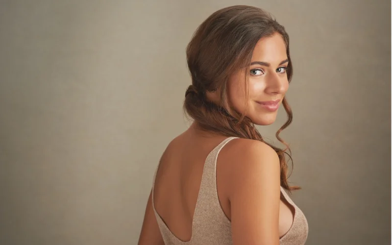 Model posing with her back to the camera in a classic implied photoshoot pose that highlights the natural curve of the spine