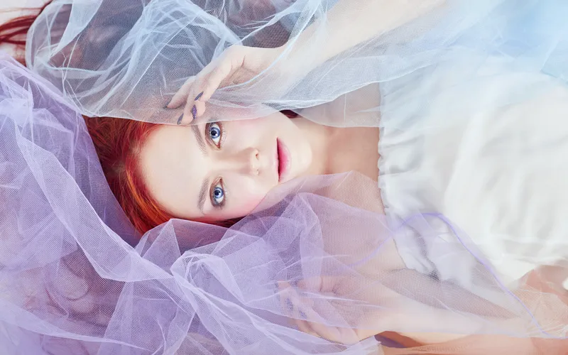 Model draped in sheer fabric for an implied boudoir photography session, using the veil to add mystery to the composition