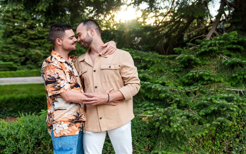 Gay couple embracing outdoors in soft golden hour light