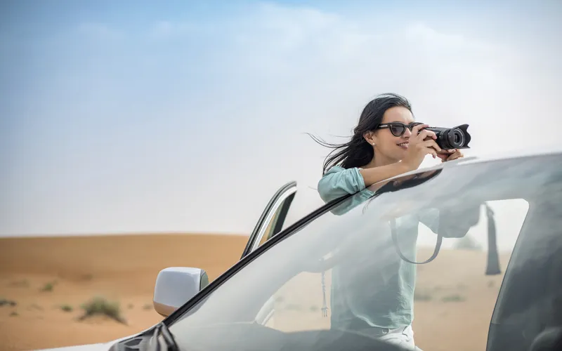 female photographer clicking pictures with her camera from a moving car