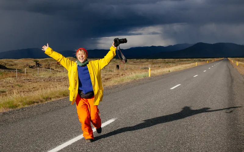 smiling woman walking with camera in her hand