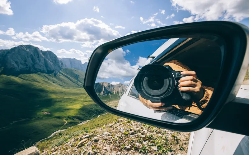camera in side view mirror of a car on a scenic route
