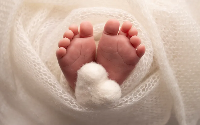 Close-up of a newborn's tiny feet against a cream knitted mat