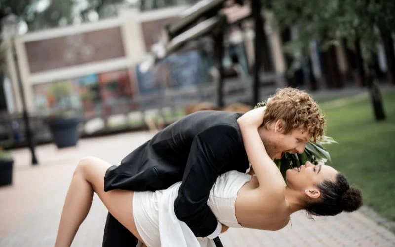 Fun couple pose with one partner dipping the other low in a graceful arch outdoors