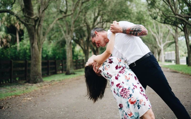 Man dipping his partner in a dramatic Hollywood-style couple pose on a tree-lined path