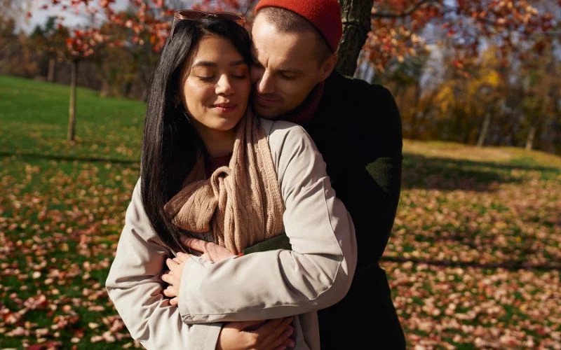 Creative couple pose of partners embracing from behind in a golden autumn field