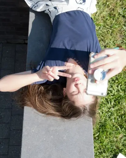 Person lying on the floor, grass, or bed while taking a creative overhead selfie with a relaxed vibe.