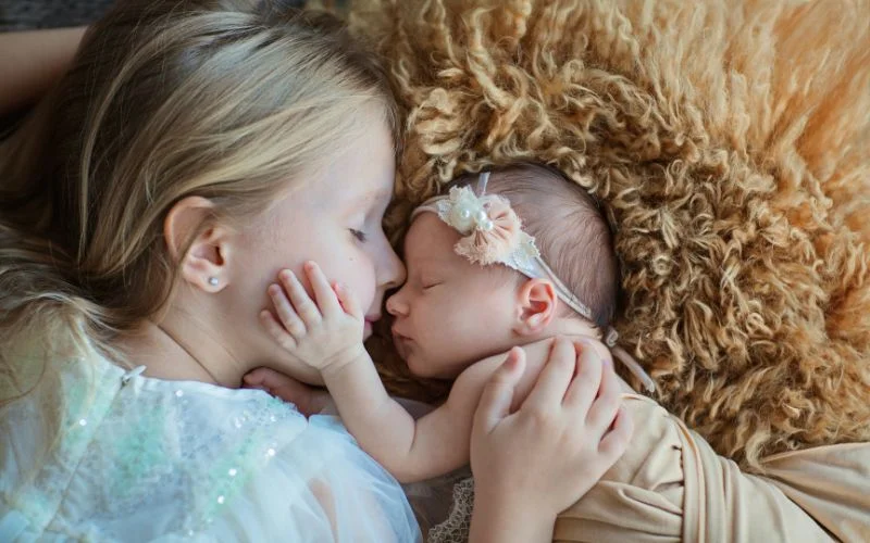 Newborn family poses showing an older sibling gently touching the baby's cheek