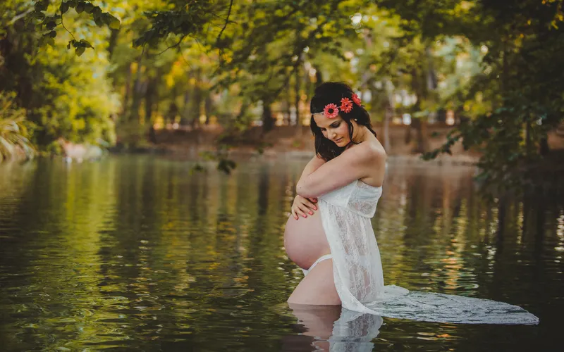 pregnant women in the lake wearing white gown and flower crown
