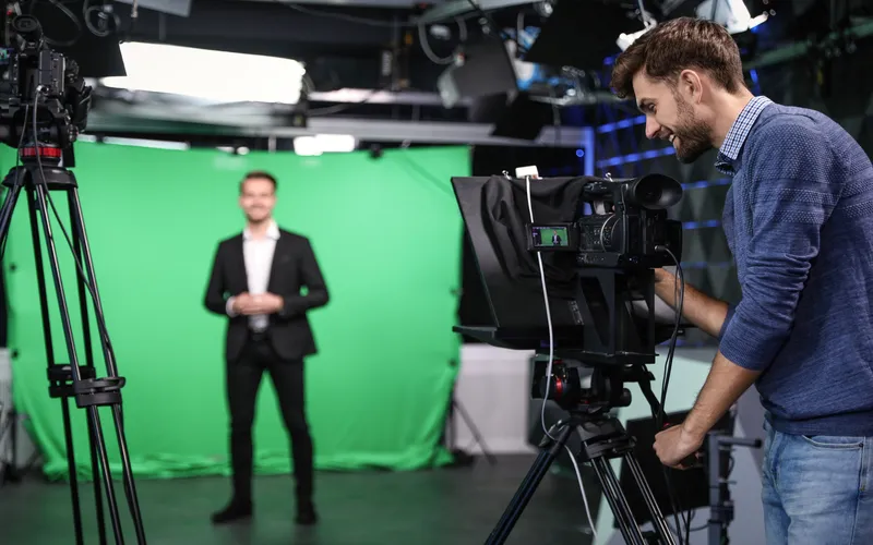 setting up of camera and lights while the camera man is shooting a man against a green screen