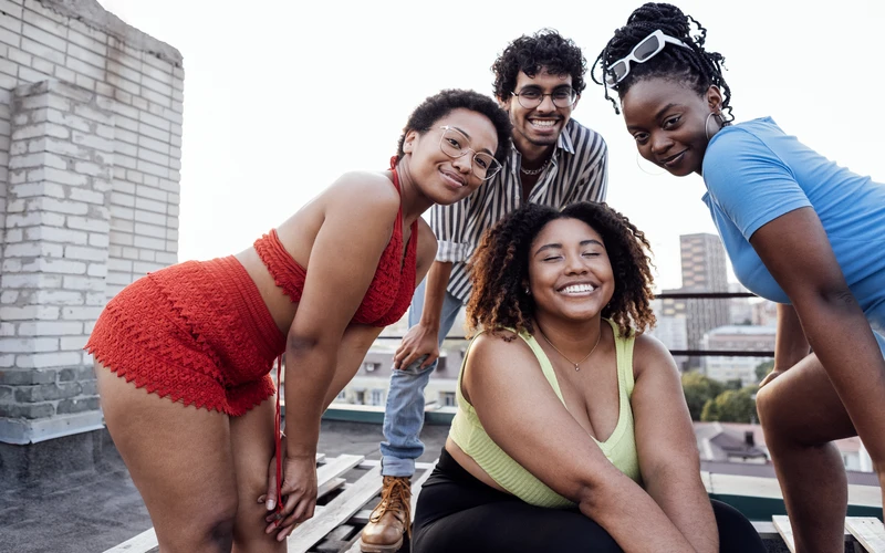 Four friends of different body types posing together on a rooftop