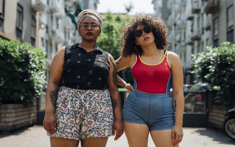 Two women walking together on a city street, photographed in soft natural light