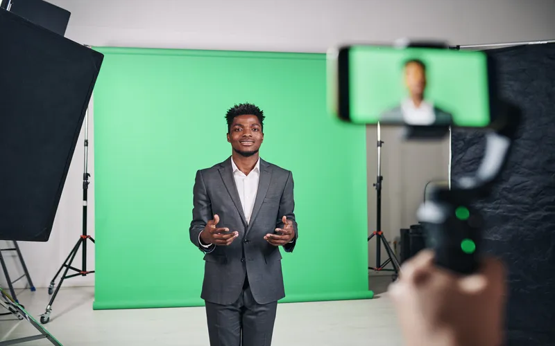 well-dressed man speaking in studio with green screen