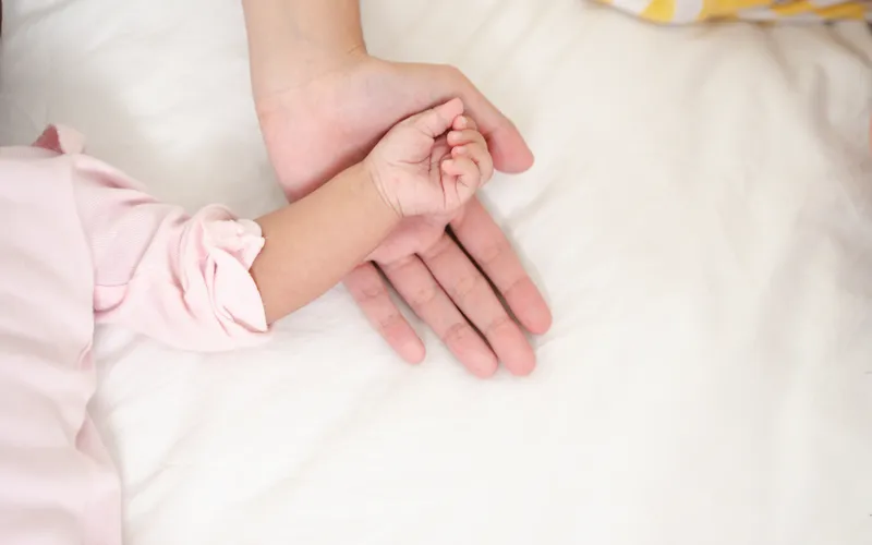 infant hand resting on adults hand