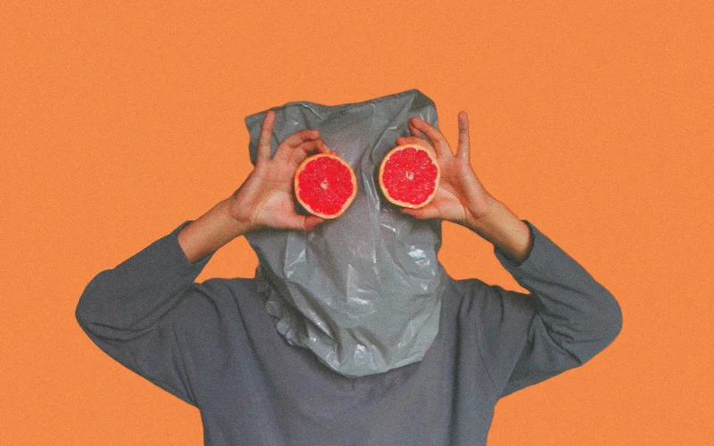 man holding orange as eyes