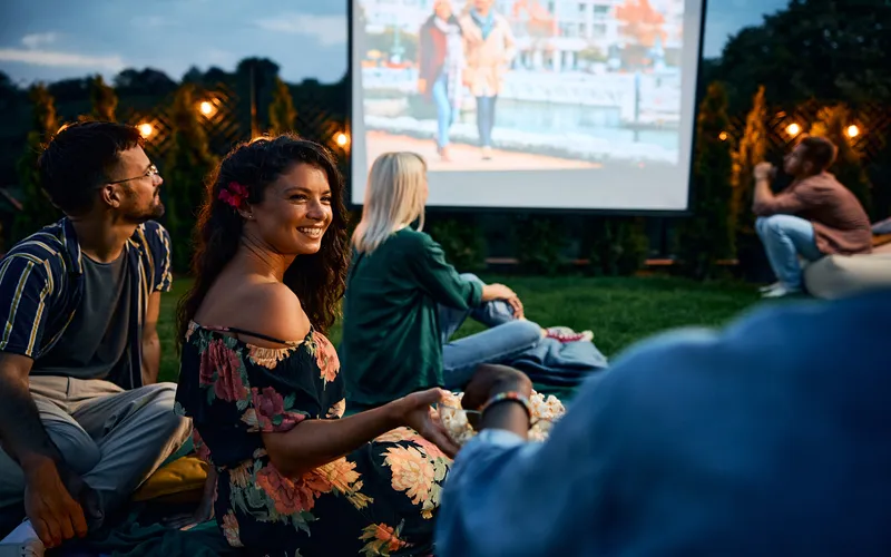 friends watching a movie on projector outdoors