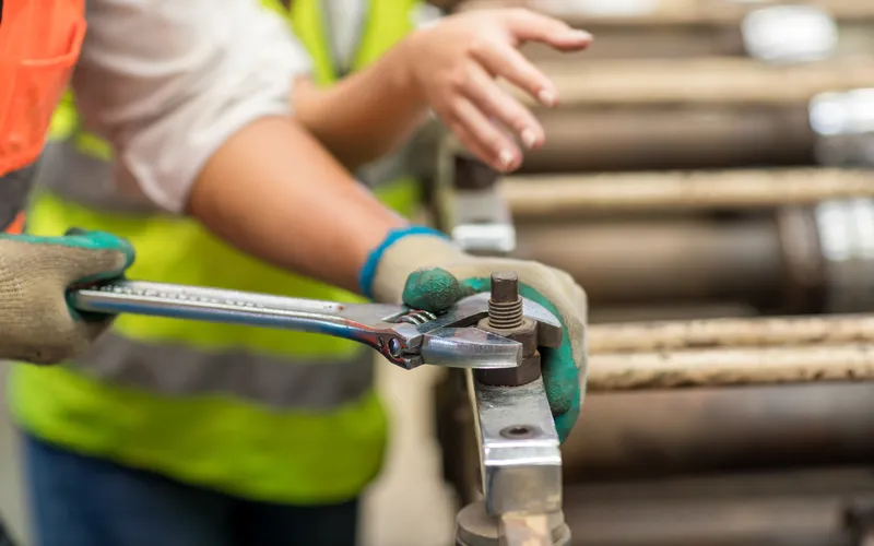 close up shot of a worker in factory using wrench