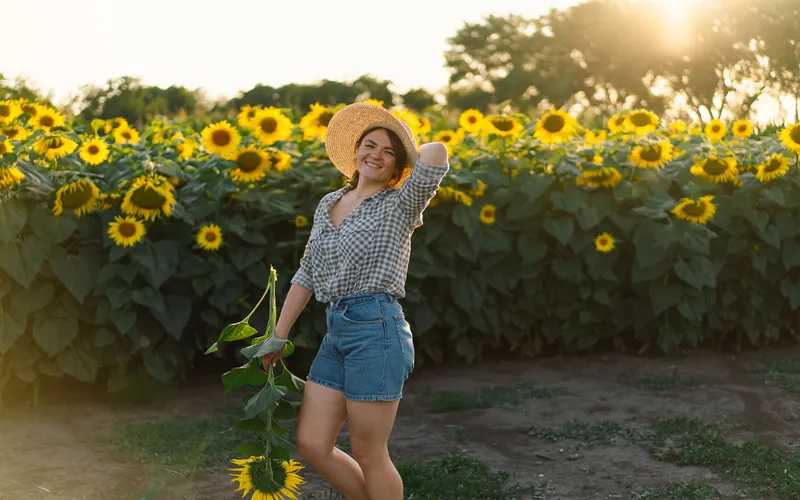 woman in cute outfit and hat posing for a photo in the sunflower field