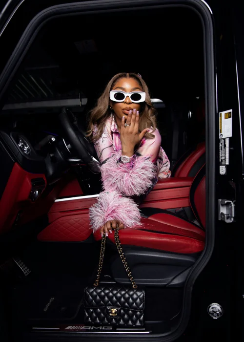 a model blowing a kiss while sitting in a car
