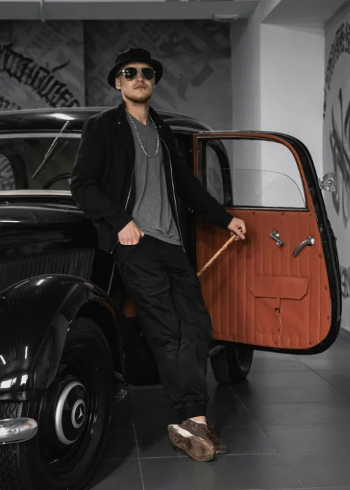 a man posing at the back of a car with the door open