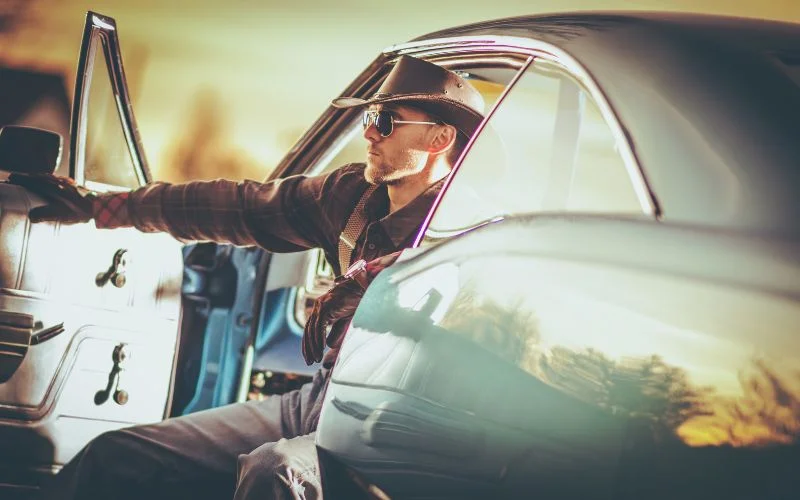a man posing at the back of a car with the door open