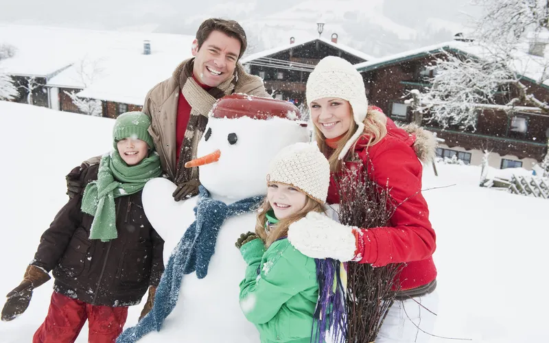 Family making snowman and posing for Christmas family photo