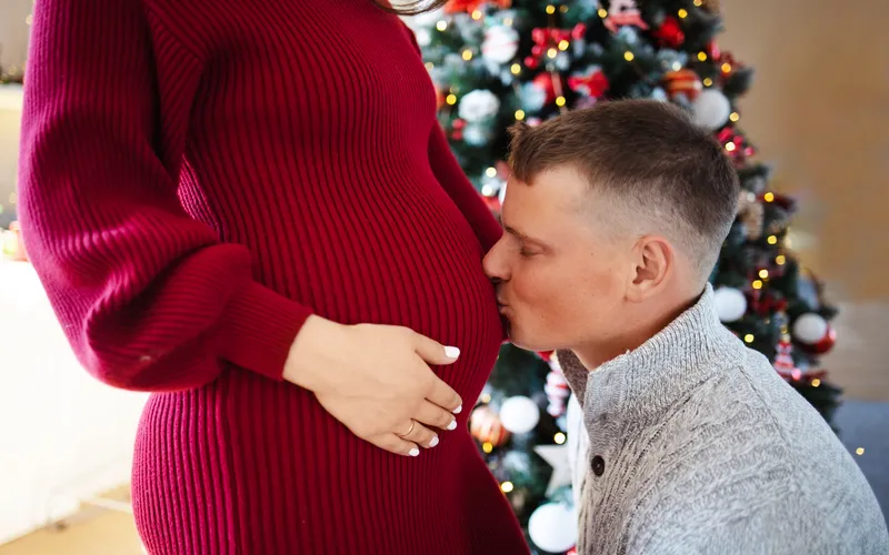 expecting couple- partner kissing the baby bump