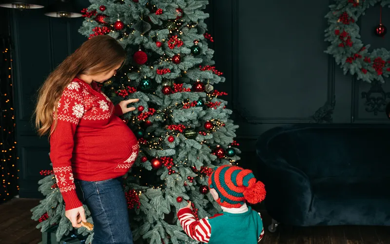 pregnant women and her child decorating Christmas tree