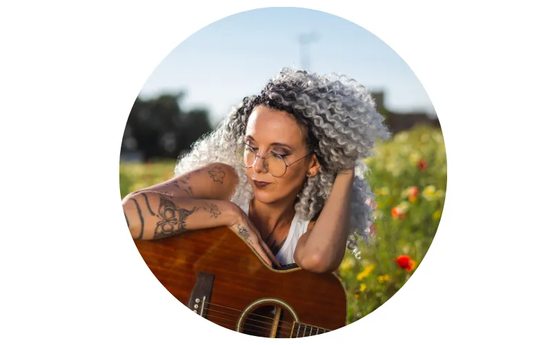 woman in grassy field with guitar