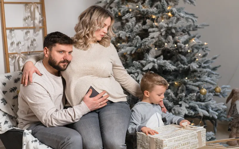 family posing for a photoshoot and highlighting the baby bump