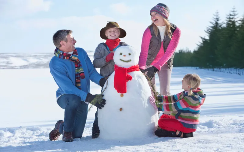 family posing for a photo while making a snowman