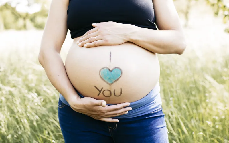 blue heart painted on the belly of a pregnant women
