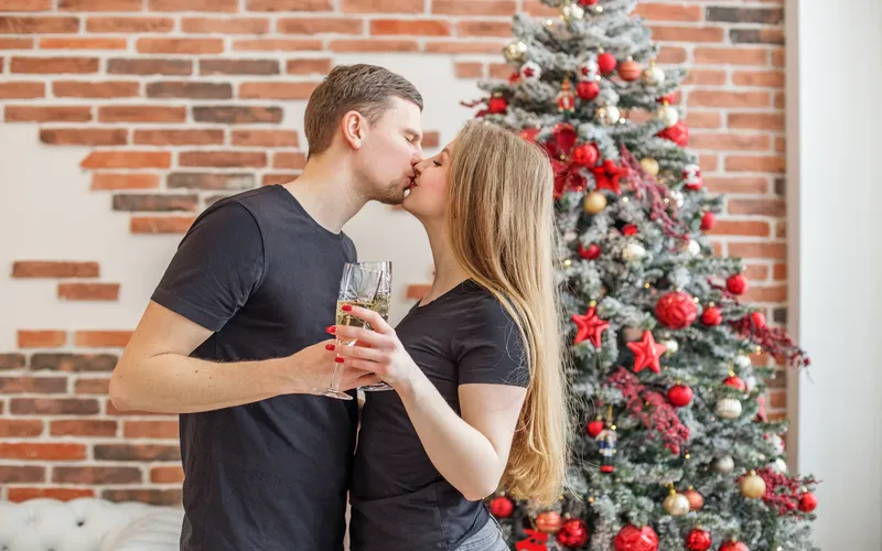 Romantic couple kissing by a Christmas tree