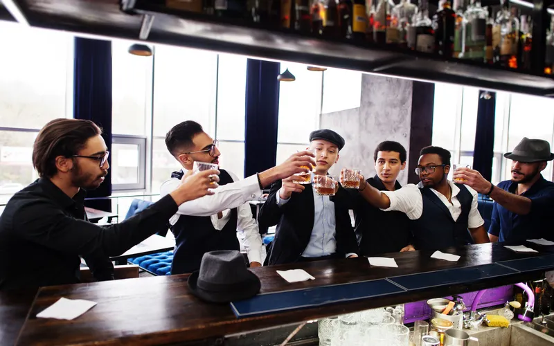 groomsmen posing for a shot with champagne glasses in their hands