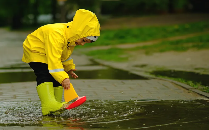 kid enjoying in the rain while wearing colorful protective gear