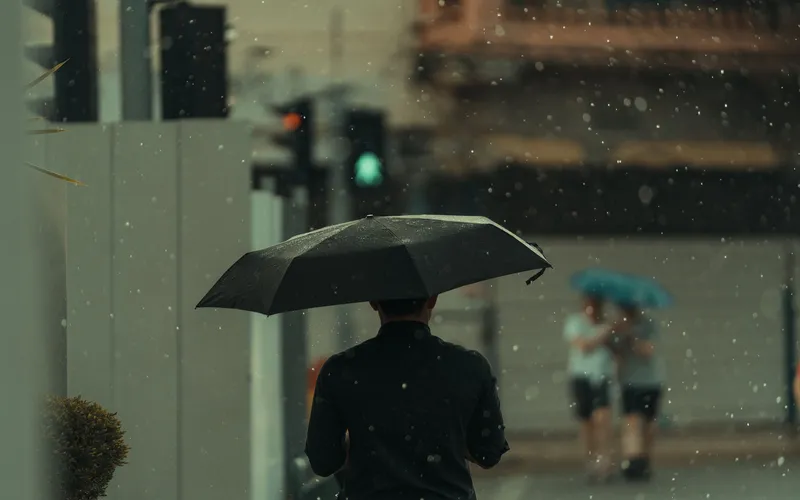 silhouette of a man in the rain holding an umbrella