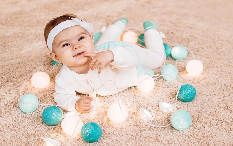 infant lying on a blanket surrounded by lights