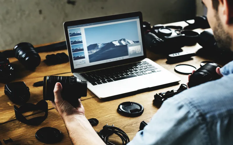 man editing photos taken from camera on his laptop