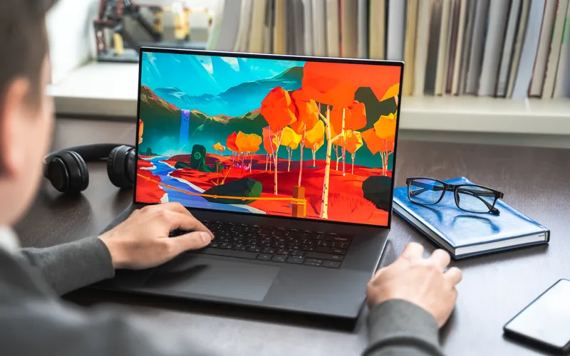 photo of a man working on his laptop with a bright image displayed on the screen