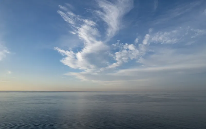 Calm ocean scene with a boat and island, clouds smoothed into streaks by a 30 second long exposure